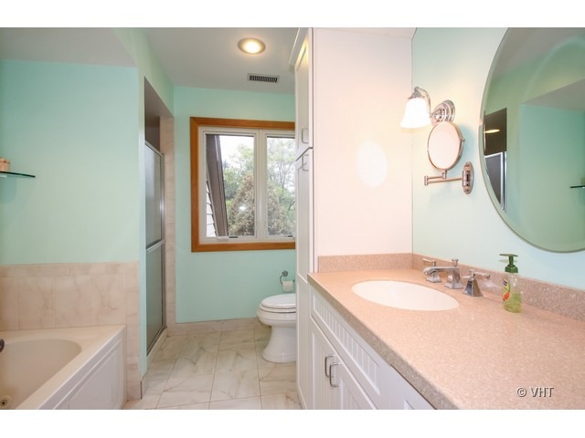 1979 Koehling Road Northbrook, IL 60062 - Photo 7 of 10 a bathroom with a granite countertop sink mirror bathtub and toilet