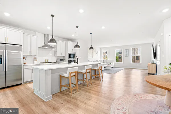a large kitchen with cabinets chairs and wooden floor
