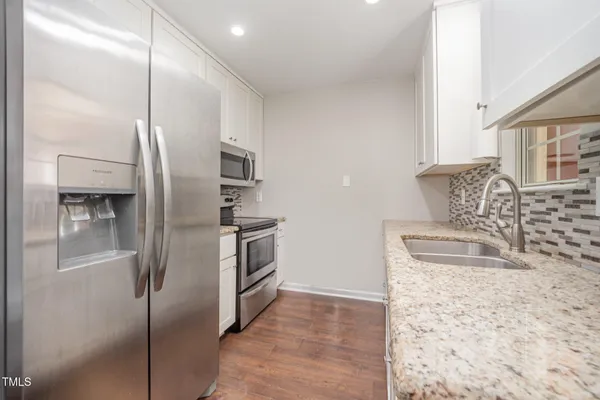a kitchen with granite countertop a refrigerator and a sink