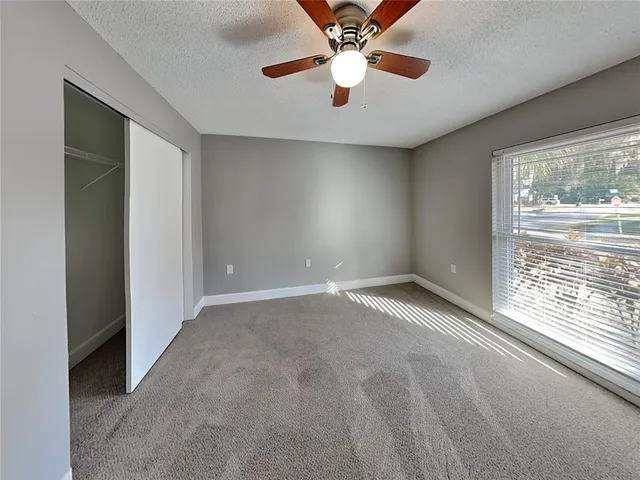 an empty room with windows and chandelier fan