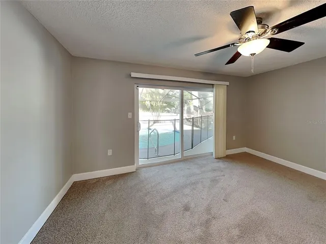 an empty room with chandelier fan and windows