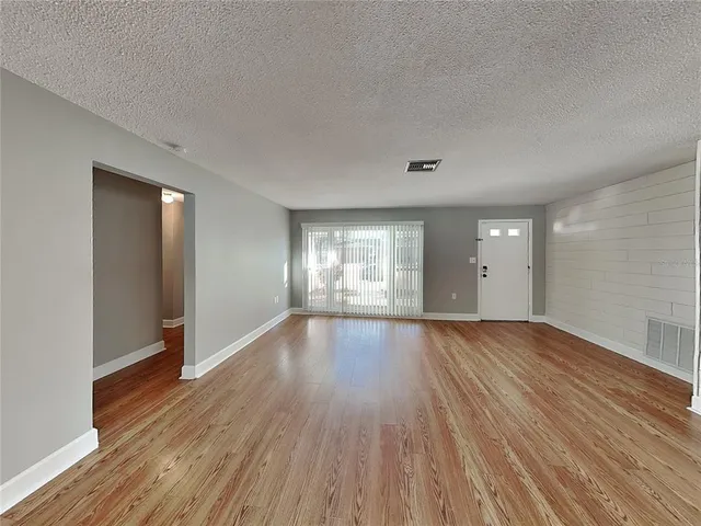 a view of empty room with wooden floor and window
