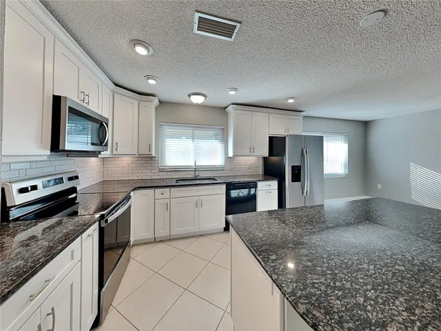 a kitchen with stainless steel appliances granite countertop a sink stove microwave and cabinets