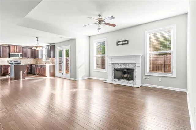 a view of a livingroom with a ceiling fan window wooden floor and a kitchen