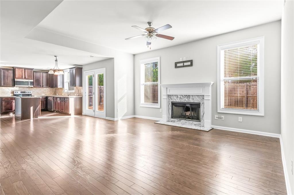 4237 Water Mill Drive Buford, GA 30519 - Photo 11 of 35 a view of a livingroom with a ceiling fan window wooden floor and a kitchen
