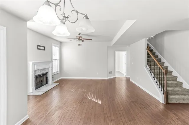 a view of an empty room with wooden floor fireplace and a window