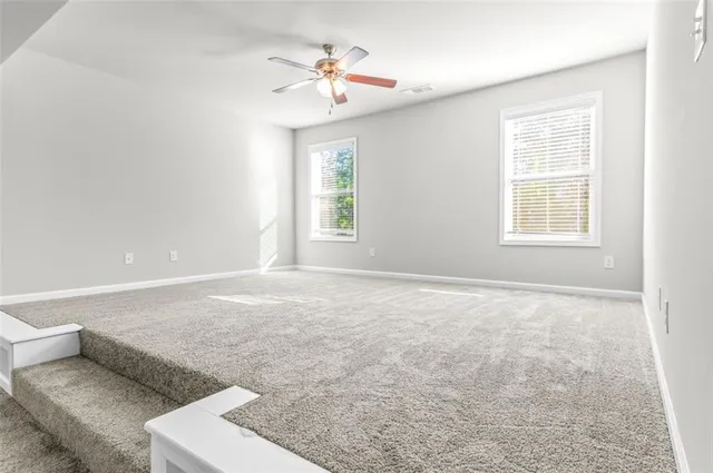 an empty room with windows and chandelier fan