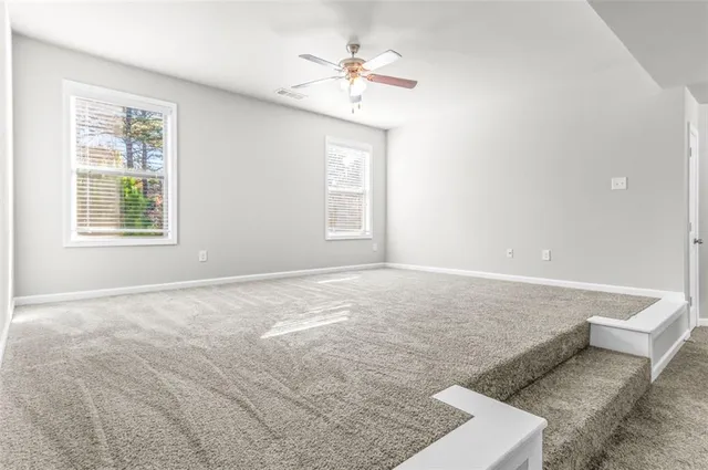 an empty room with windows and ceiling fan