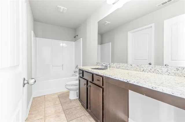 a bathroom with a granite countertop sink a toilet and a shower