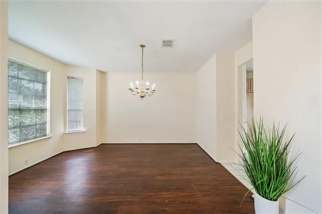 a view of empty room with wooden floor and potted plants