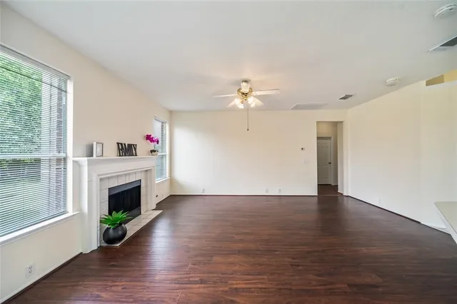 a view of an empty room with window and wooden floor