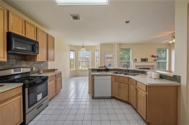 a kitchen with stainless steel appliances granite countertop a stove top oven a sink dishwasher and a microwave oven on the blue kitchen countertops