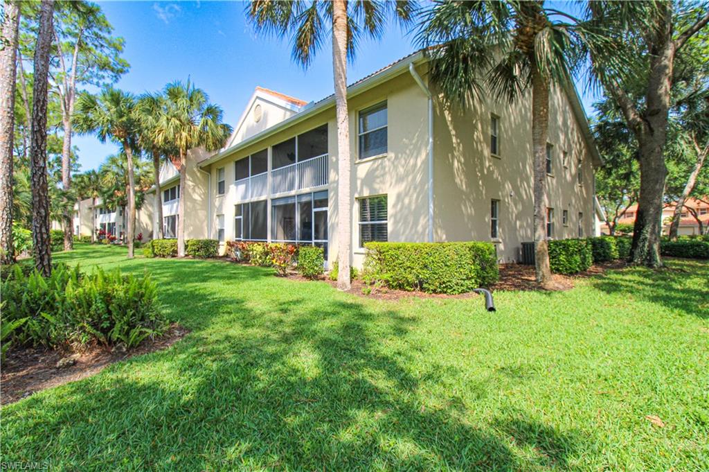 225 Robin Hood Circle, Unit 203 Naples, FL 34104 - Photo 3 of 50 Back of property featuring a yard and central air condition unit