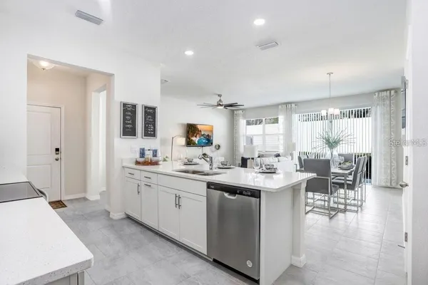 a kitchen with stainless steel appliances kitchen island granite countertop a dining table chairs and refrigerator