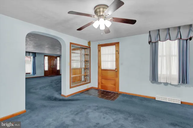a view of an empty room with window and chandelier fan