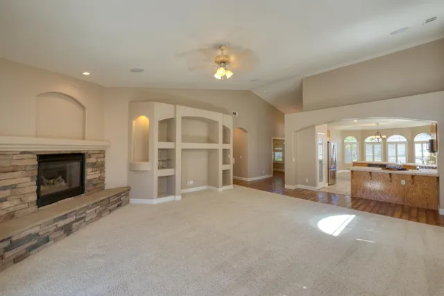 an empty room with ceiling fan and windows