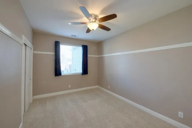 an empty room with closet and a ceiling fan