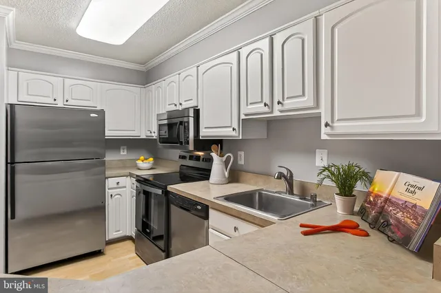 a kitchen with stainless steel appliances granite countertop a refrigerator sink and white cabinets