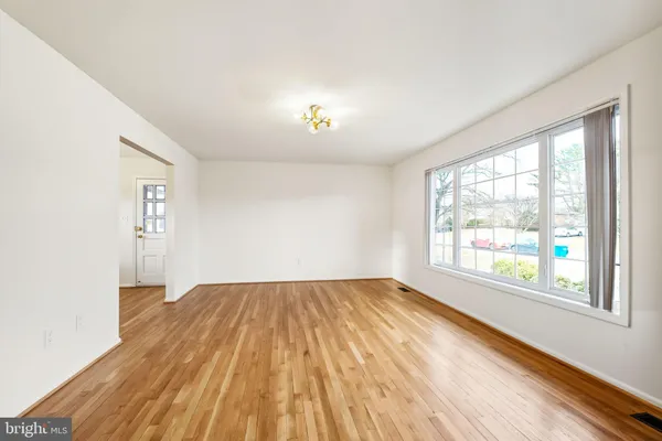 a view of an empty room with a window and hardwood floor