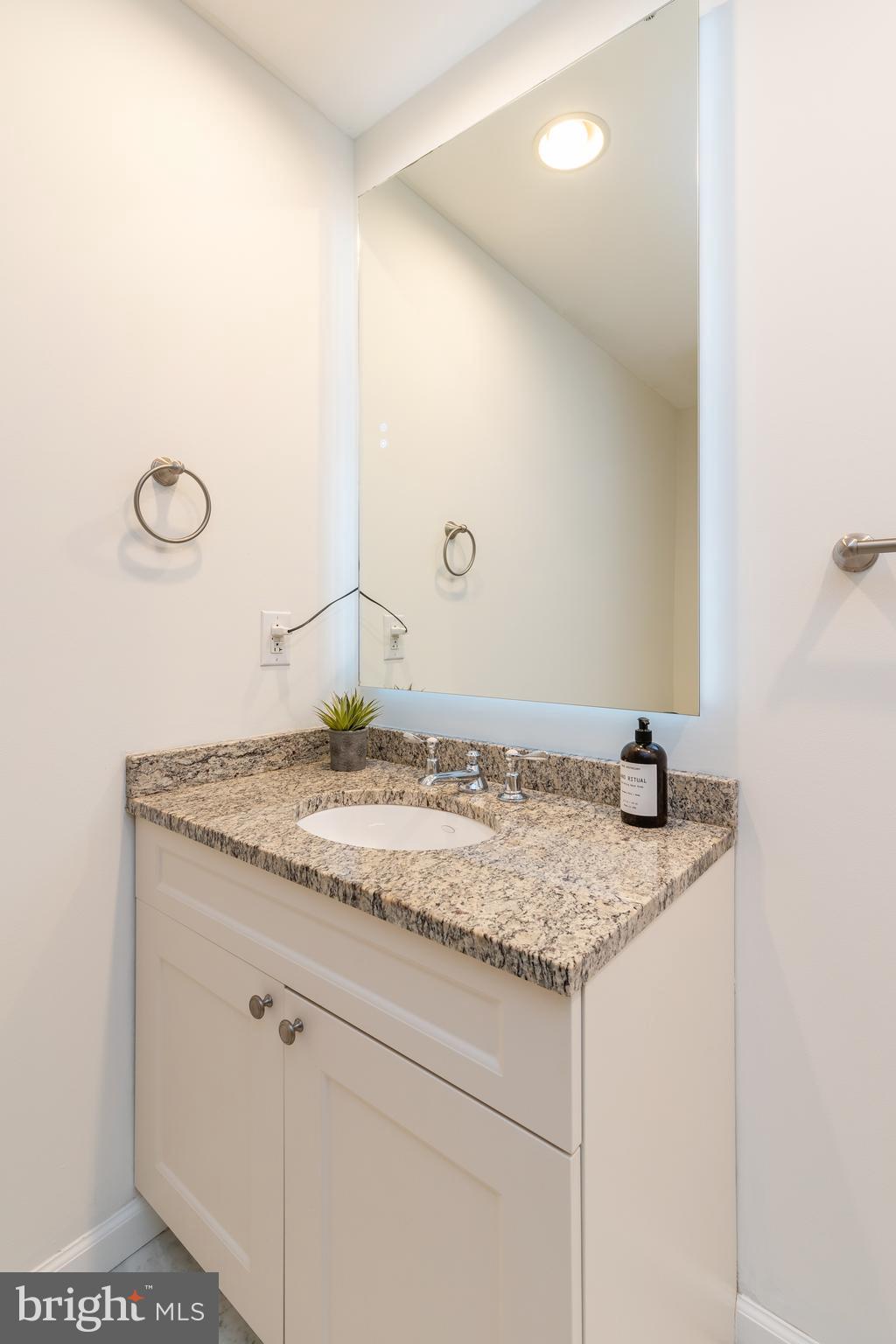 1811 Chestnut Street, Unit 707 Philadelphia, PA 19103 - Photo 13 of 39 a bathroom with a granite countertop sink and a mirror