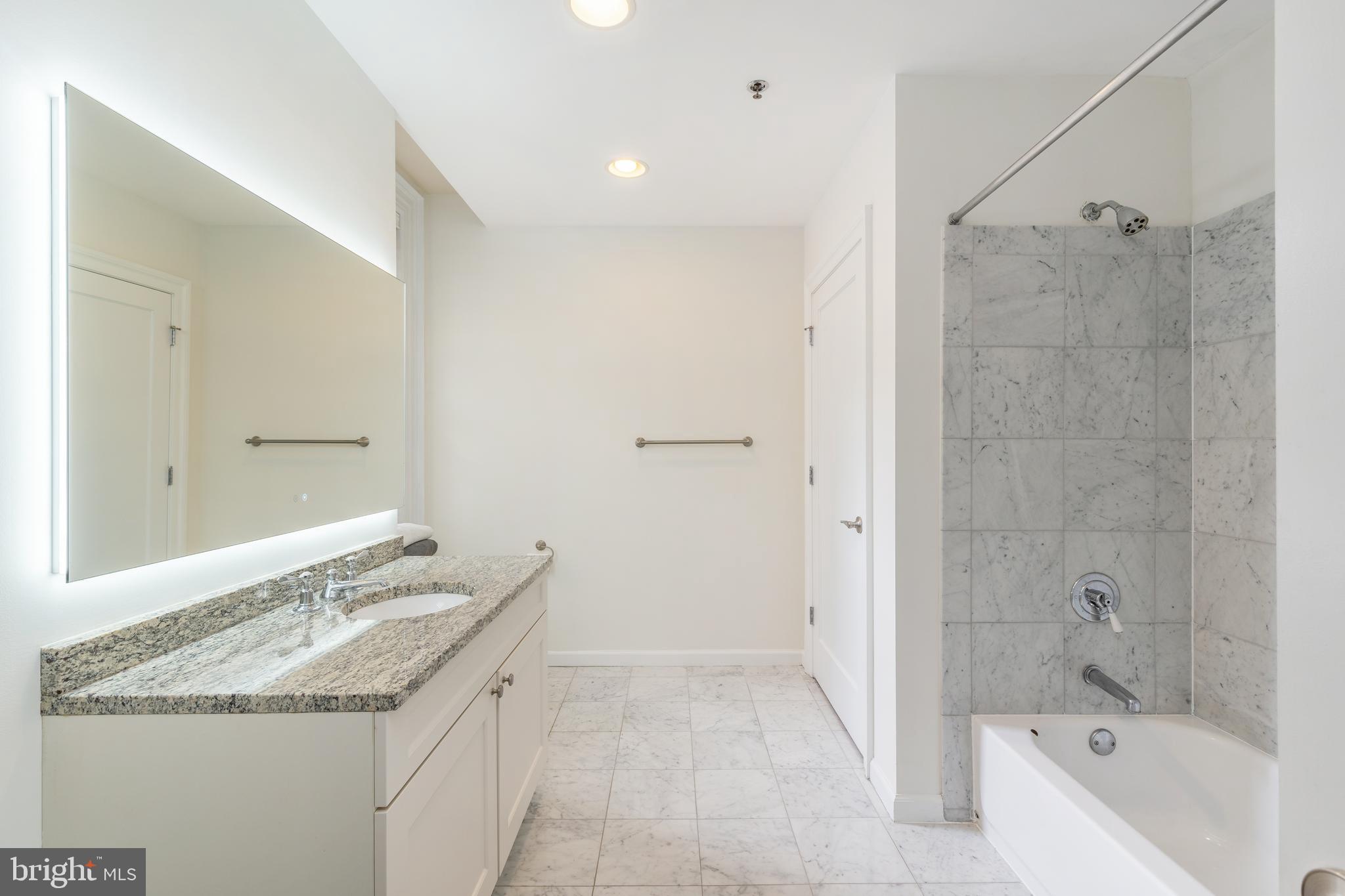 1811 Chestnut Street, Unit 707 Philadelphia, PA 19103 - Photo 18 of 39 a bathroom with a granite countertop sink a mirror and a bathtub