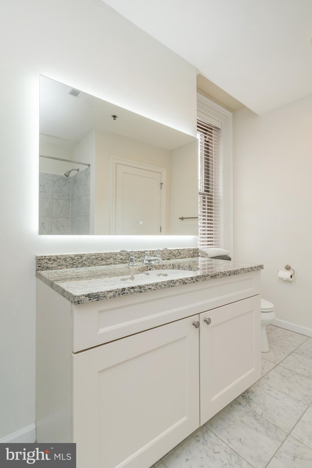 1811 Chestnut Street, Unit 707 Philadelphia, PA 19103 - Photo 19 of 39 a bathroom with a granite countertop sink and a mirror