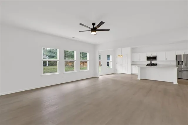 a view of a livingroom with a ceiling fan & windows