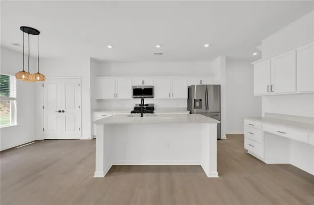 a view of kitchen with stainless steel appliances refrigerator stove microwave and cabinets