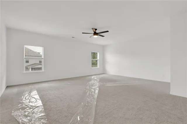 an empty room with windows and ceiling fan