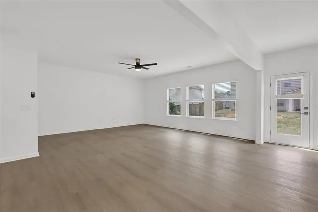 a view of an empty room with a window and wooden floor