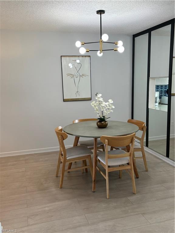315 St Andrews Boulevard, Unit A2 Naples, FL 34113 - Photo 14 of 17 Dining room with light wood finished floors, a textured ceiling, and a chandelier