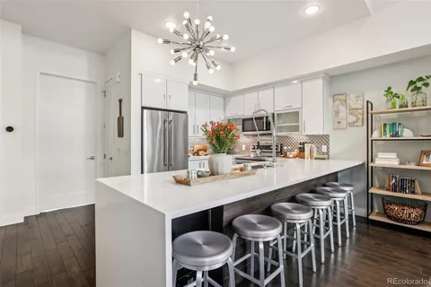 a kitchen with kitchen island a dining table chairs stainless steel appliances and cabinets