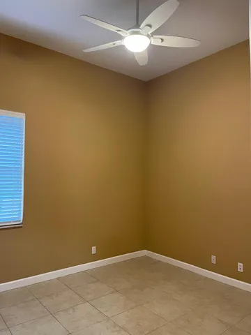 an empty room with a ceiling fan and a window