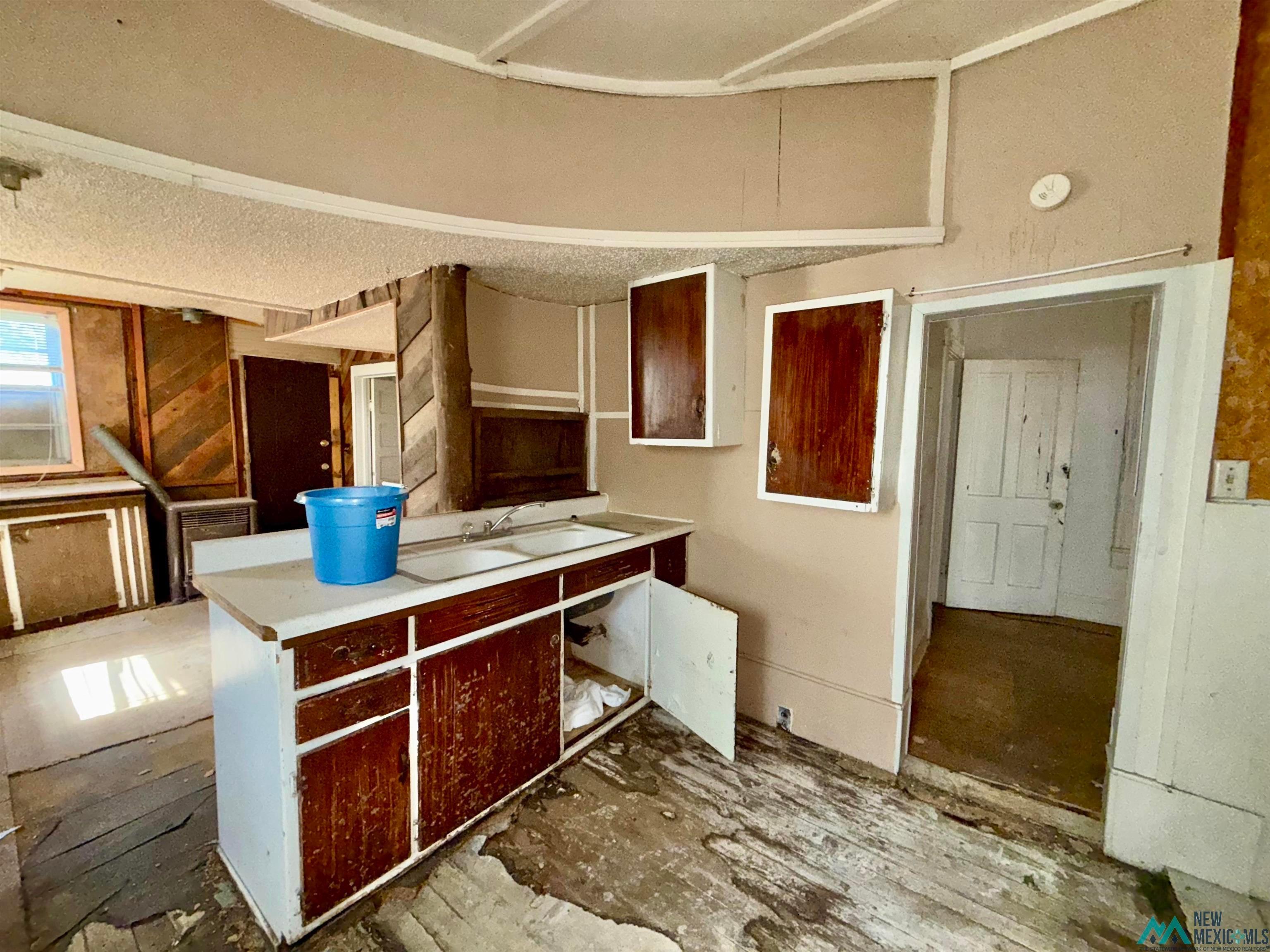 237 Vermejo Street Raton, NM 87740 - Photo 5 of 14 Kitchen with light countertops, a textured ceiling, and wood walls