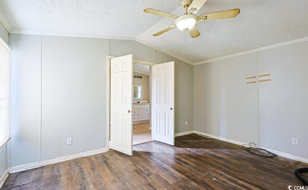 175 Darlene Drive Myrtle Beach, SC 29588 - Photo 11 of 31 Unfurnished bedroom featuring a textured ceiling, ornamental molding, lofted ceiling, dark wood finished floors, and a ceiling fan