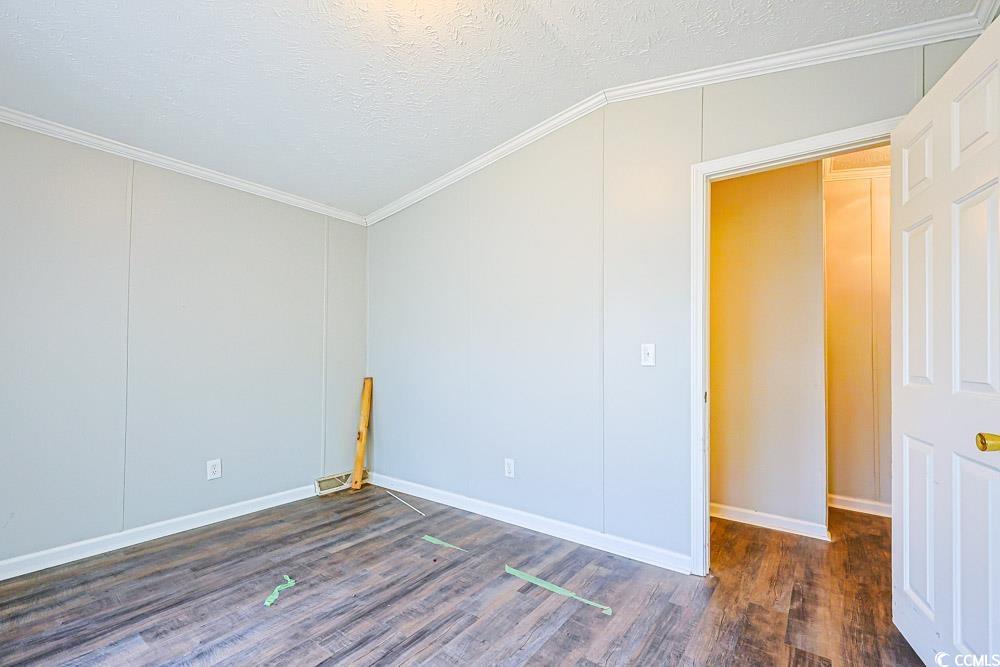 175 Darlene Drive Myrtle Beach, SC 29588 - Photo 18 of 31 Empty room featuring dark wood finished floors, a textured ceiling, ornamental molding, and lofted ceiling