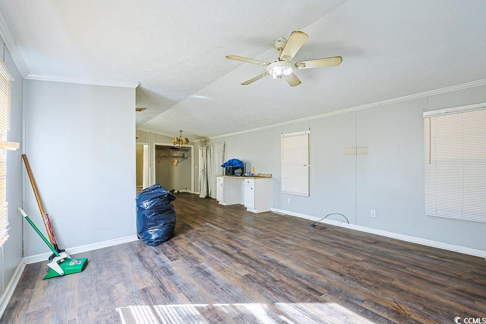 175 Darlene Drive Myrtle Beach, SC 29588 - Photo 5 of 31 Unfurnished living room with crown molding, lofted ceiling, dark wood-style flooring, ceiling fan, and a textured ceiling