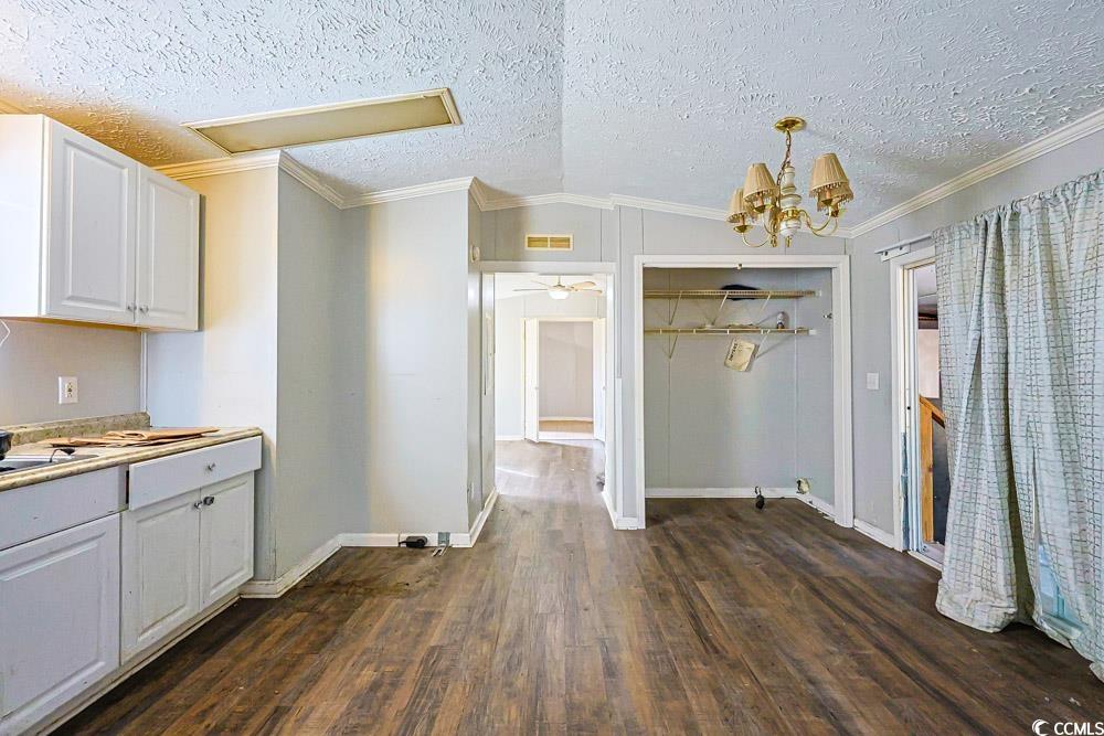 175 Darlene Drive Myrtle Beach, SC 29588 - Photo 9 of 31 Unfurnished dining area featuring crown molding, a textured ceiling, dark wood-type flooring, a chandelier, and lofted ceiling
