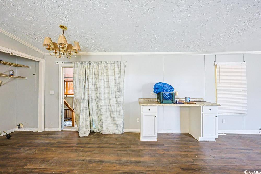 175 Darlene Drive Myrtle Beach, SC 29588 - Photo 10 of 31 Unfurnished dining area featuring a textured ceiling, a desk, crown molding, dark wood finished floors, and a chandelier