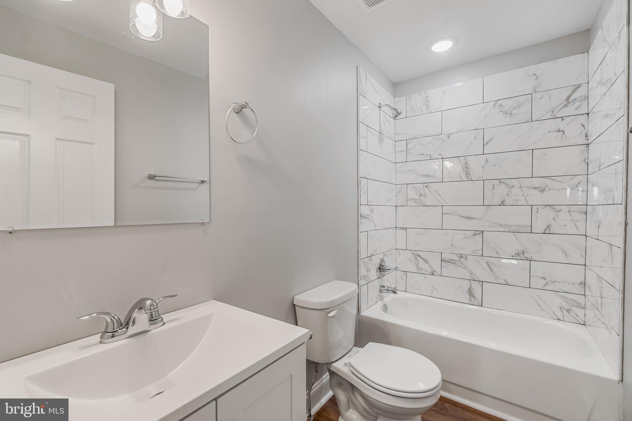 a bathroom with a bathtub shower sink vanity and toilet