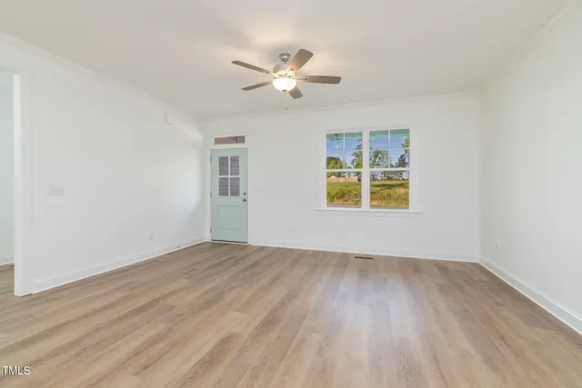 a view of an empty room with wooden floor and a window