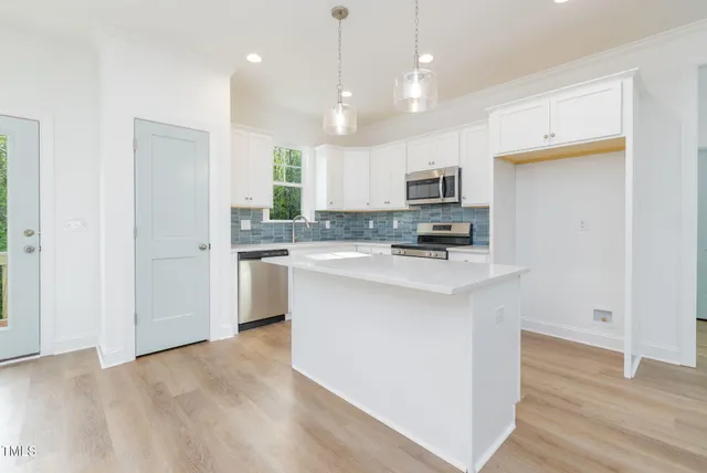 a kitchen with kitchen island a sink stainless steel appliances and white cabinets