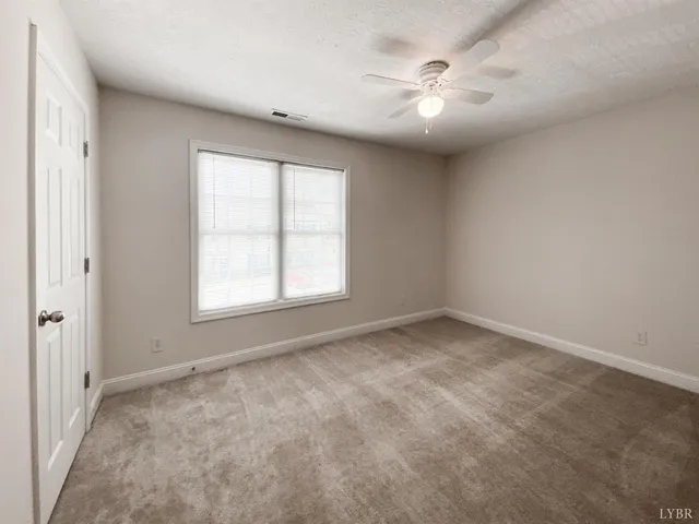 an empty room with windows and chandelier fan