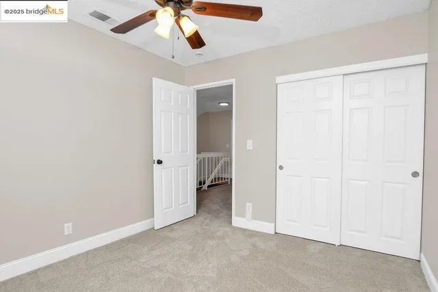 an empty room with a ceiling fan and carpet