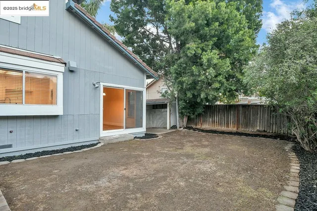 a view of a white house with a large tree and wooden fence