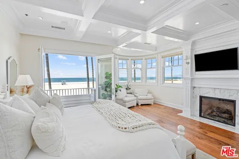 a bedroom with a large bed couch and a large window with wooden floor