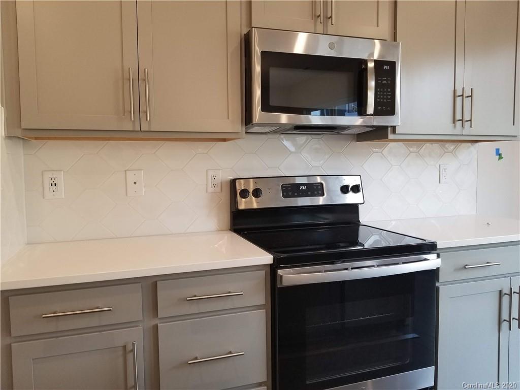 514 Madison Falls, Unit 7 Fort Mill, SC 29708 - Photo 3 of 12 a kitchen with stainless steel appliances granite countertop white cabinets and a stove top oven