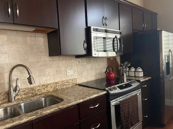 a kitchen with granite countertop a sink stainless steel appliances and cabinets