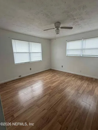 an empty room with wooden floor and windows