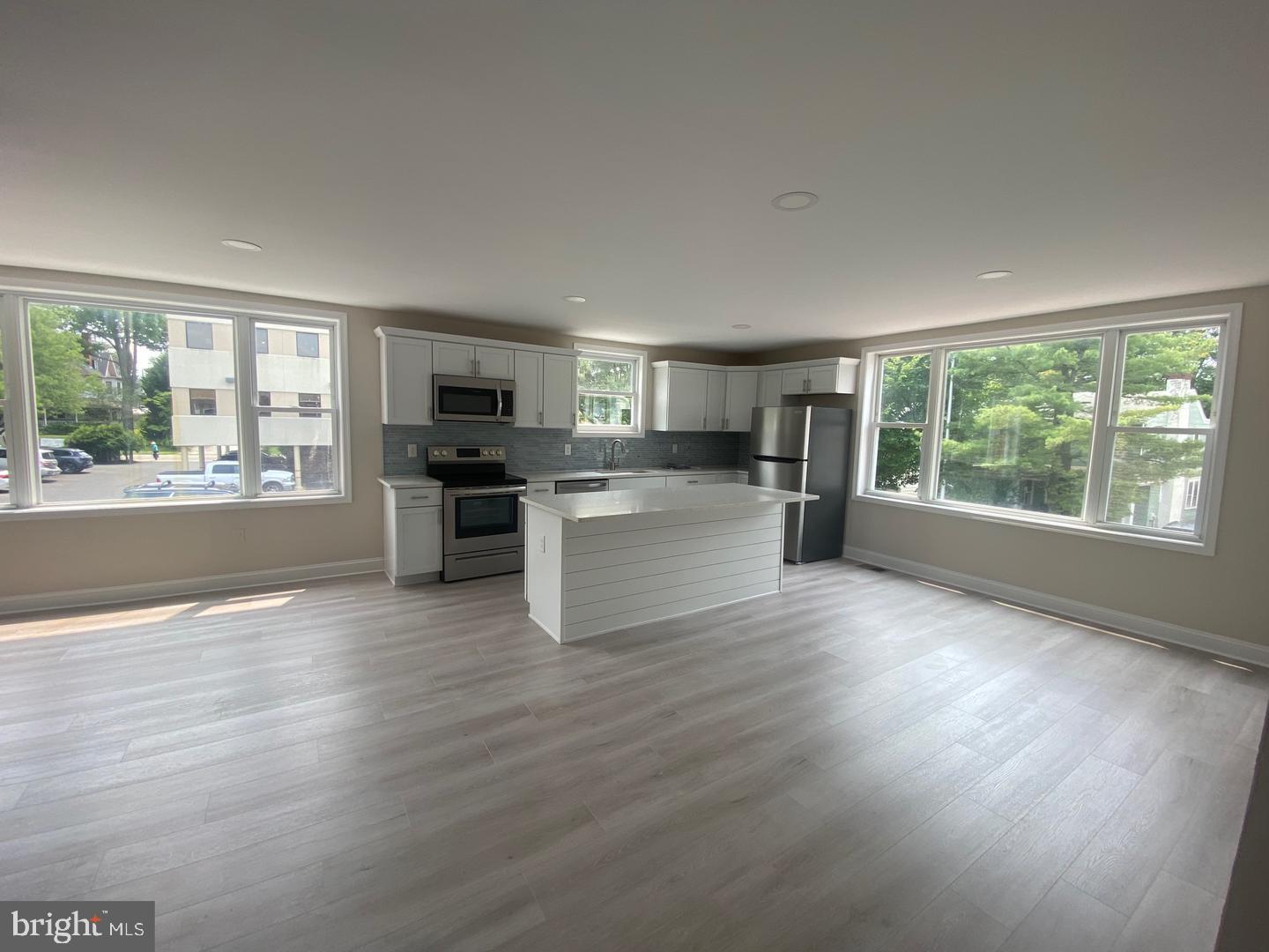 a view of a kitchen and an empty room with wooden floor kitchen view